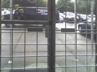 Light grey steel door bars attached to a store front glass doors.